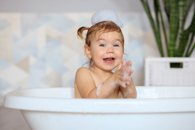 Happy baby bathes in the bathroom