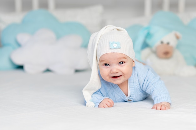 Happy baby on the bed in a hood. Textiles and bedding for children. Newborn baby with a toy bear