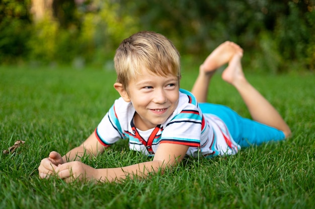 屋外レクリエーションの休日幸せな子供時代を笑顔の草の上に横たわる青い目をした金髪の幸せな赤ちゃん