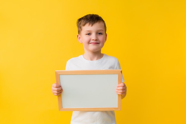 Happy baby boy of 7 years in a white T-shirt on a yellow background