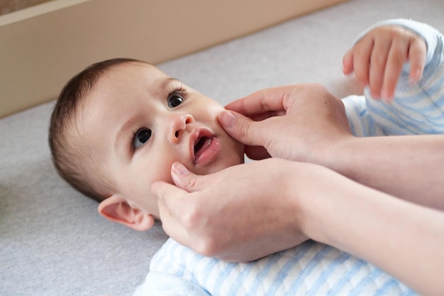 Happy Baby boy lying mother's hand pressing her cheeks