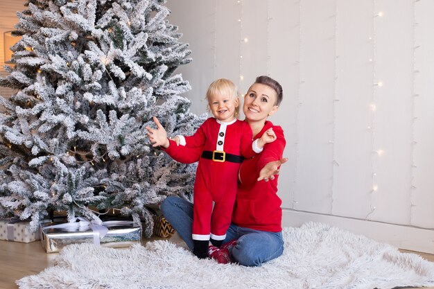 Счастливый мальчик и мать в празднично украшенной комнате на Рождество