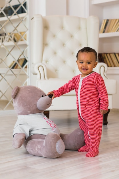 Happy baby boy playing with his teddy bear.