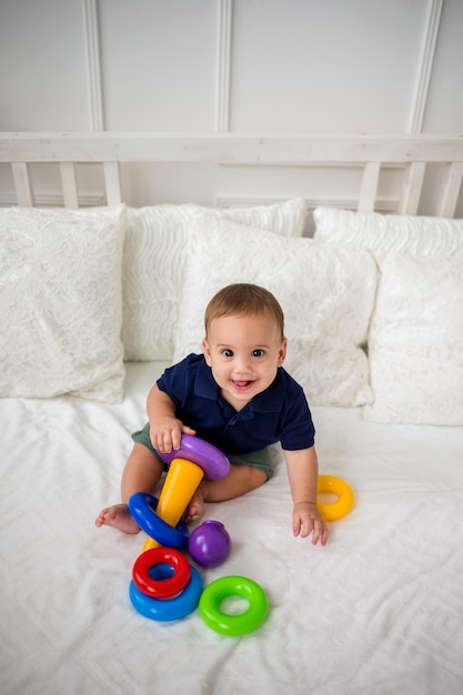 Happy baby boy and plays with a pyramid toy. The view from the top