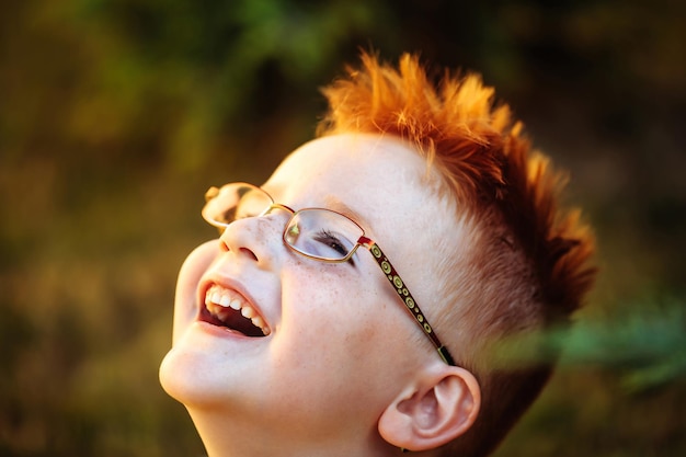 Happy baby boy with red hair in glasses