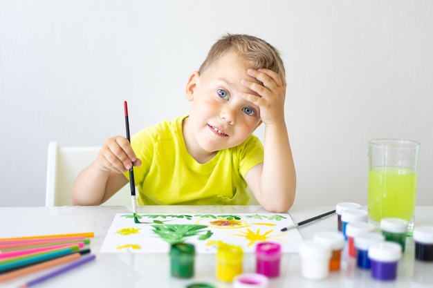 Happy baby the child draws with a brush with bright colors\
smiles looks at the camera