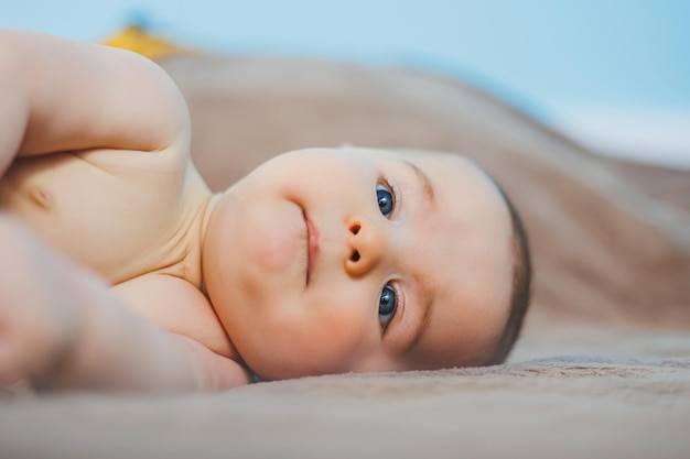 4개월 된 행복한 아기가 니트 담요 위에 누워 있다 아기 초상화 머리를 안고 있는 아이