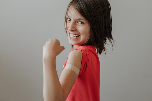 Foto bambina felice dopo la vaccinazione con un cerotto sulla spalla
