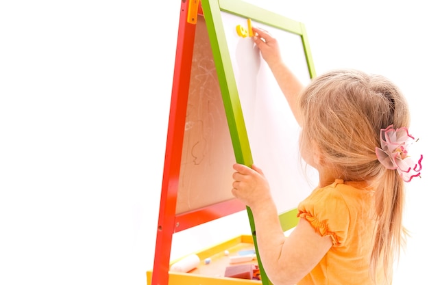 Happy baby girl beautiful painting on the easel on a white background