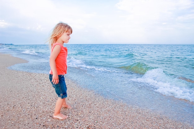 Happy baby girl on the sea in the summer on the nature