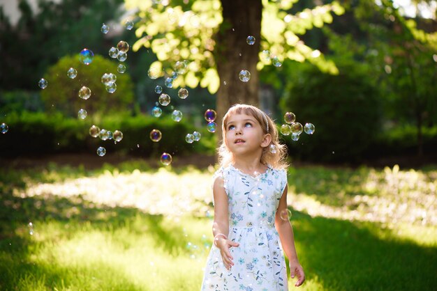 Happy baby girl standing in grass with dandelions