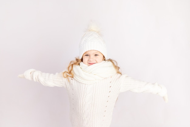 Happy baby girl in warm hat and sweater on white isolated background