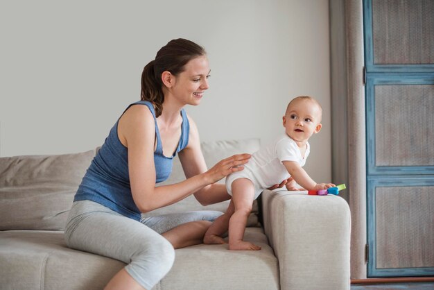 Happy baby girl with mother playing on couch