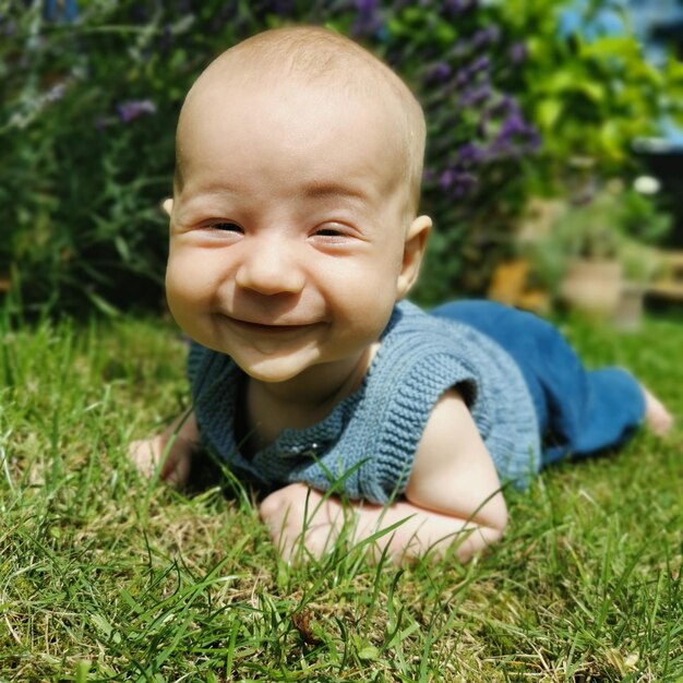 A happy baby is lying on the grass