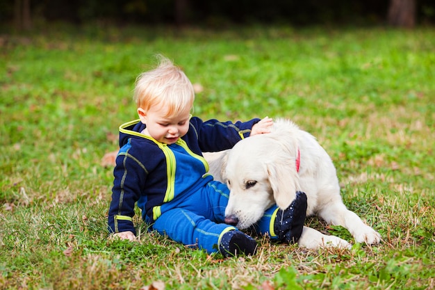 The happy baby on the lawn with his dog