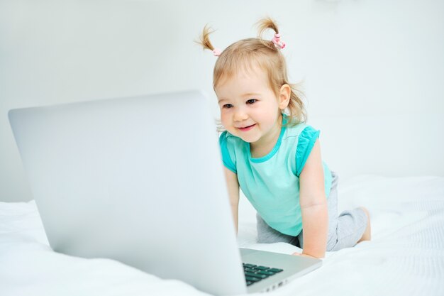 Happy baby looking at laptop sitting in bed