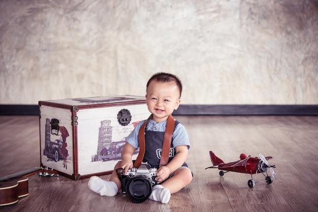 Bambino felice che gioca con la macchina fotografica classica e un modello di aereo. stile tono vintage