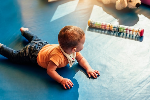 Happy baby playing with toy blocks in the kindergarten.