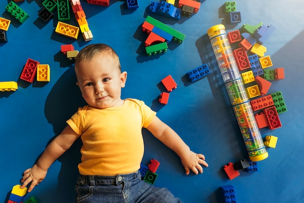 Happy baby playing with toy blocks in the kindergarten.