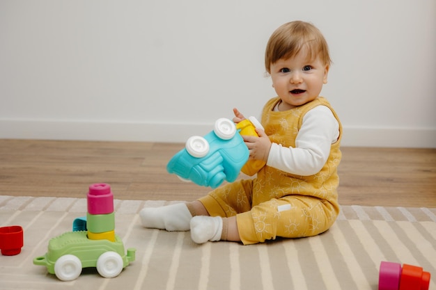 カラフルなおもちゃで遊んで幸せな赤ちゃんの肖像画小さな子供がカラフルな電車で遊んでいます。