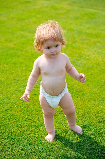 Happy baby running in a spring field and wearing a diaper first step