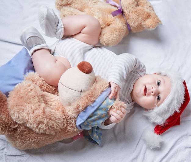 Happy baby in Santa's hat with soft toys