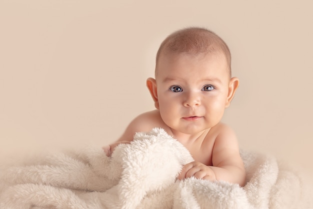 Happy baby on simple background in studio on fluffy blanket