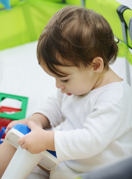 Happy baby sitting on bed playing with toys