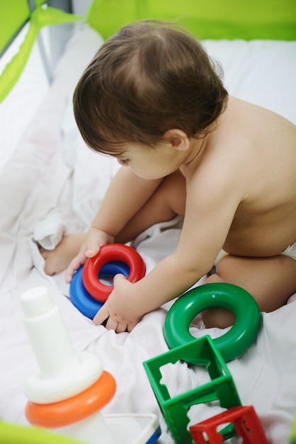 Happy baby sitting on bed playing with toys