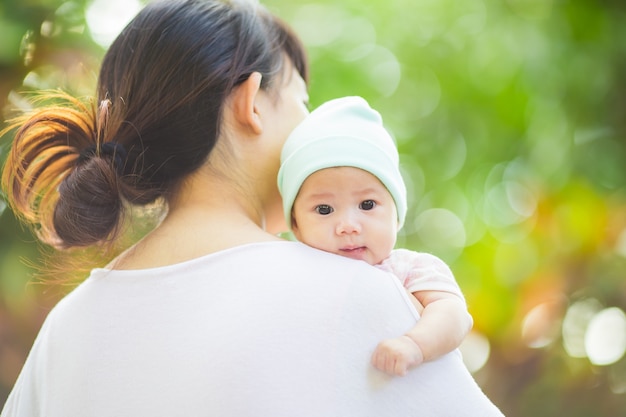 笑顔と庭で彼女の母親と遊んでいる幸せな赤ちゃん。