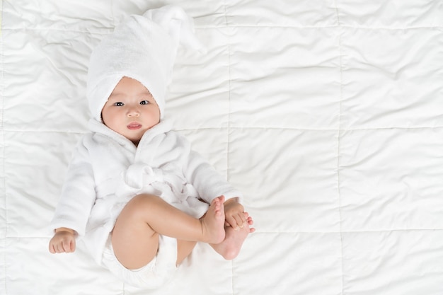 Happy baby in soft bathrobe on a bed