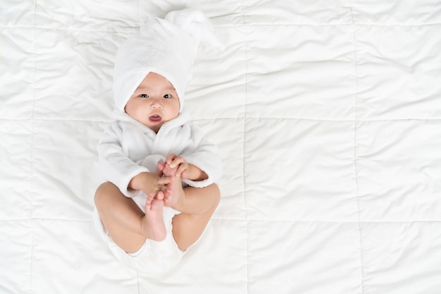 Happy baby in soft bathrobe on a bed