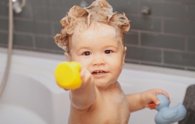 거품 거품을 가지고 노는 목욕을 하는 행복한 아기 욕조에 있는 어린 아이 욕실에서 웃는 아이
