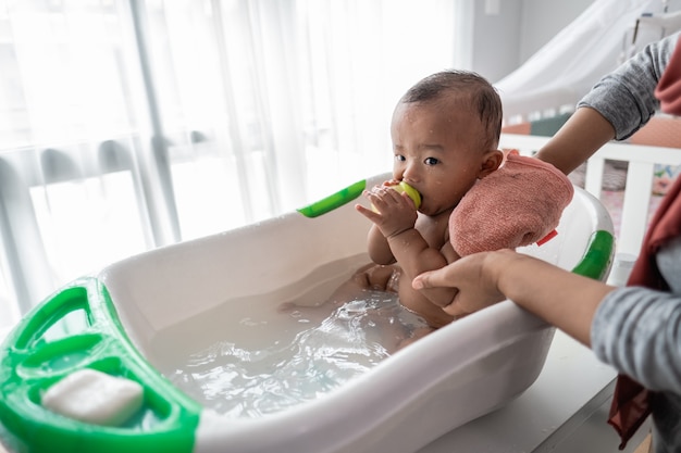 Happy baby taking a bath with mother