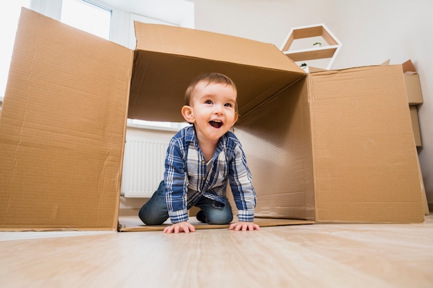 Фото Счастливый малыш малыш ползет в открытой картонной коробке дома