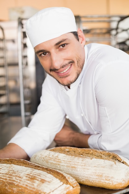 Happy baker holding tray of fresh bread