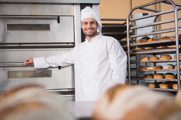 Panettiere felice che si appoggia sul forno professionale