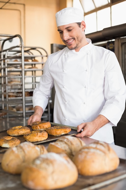 Happy baker taking out fresh bagels