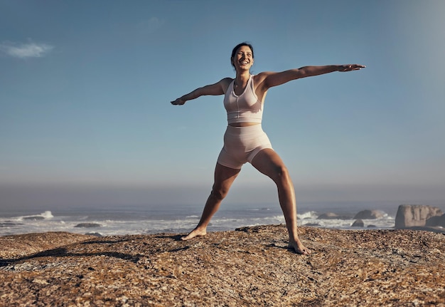 Счастливая поза баланса и йога женщины на пляже для оздоровительного дзен и мира на фоне голубого неба Улыбка стоя и медитация девушкой на растяжке в море для энергетических упражнений и фитнес-тренировок