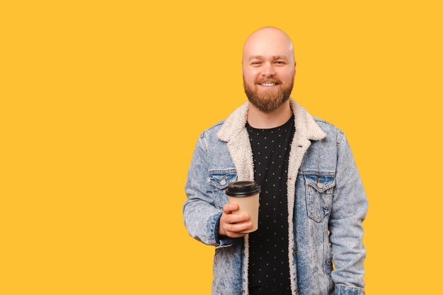 Happy bald man wearing jeans jacket enjoying his take away coffee cup