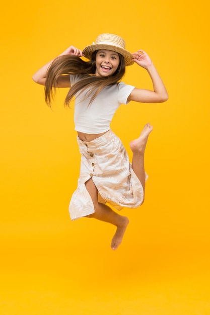 Happy barefoot child jump carefree childhood happiness small girl wear summer outfit summer vacation fashion happy childrens day having fun on beach party kid in straw hat