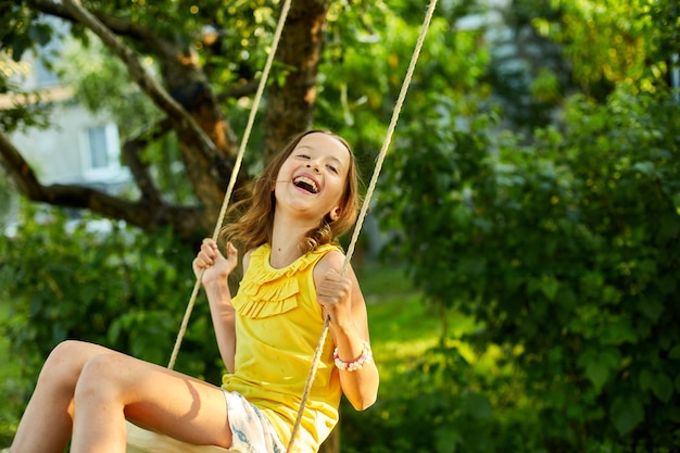 Happy barefoot laughing child girl swinging on a swing in sunset summer day