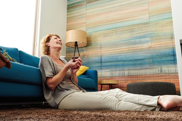 Happy barefoot woman holding mug of warm coffee