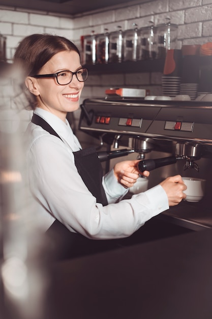 Happy barista woman in apron makes coffee to client