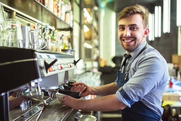 The happy barista working with a coffee machine on the bar