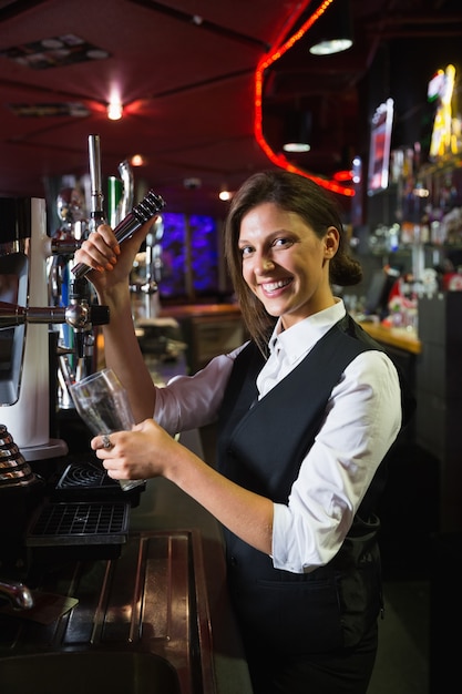 Photo happy barmaid pulling a pint of beer