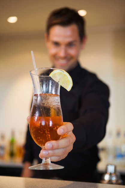 Happy bartender offering cocktail to camera