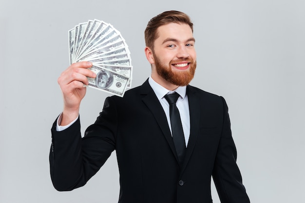 Happy bearded business man in black suit holding money in hand