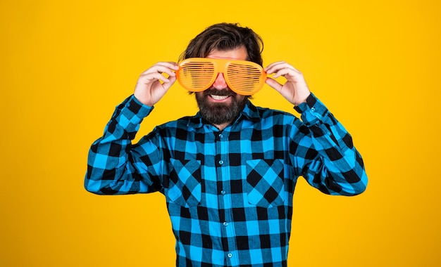 happy bearded guy wearing funny party glasses and checkered shirt on yellow background lets celebrate