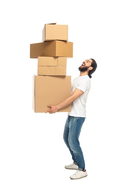 Счастливый бородатый латиноамериканец держит картонные коробки и улыбается изолированно на белом